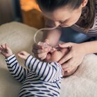 Niedawno narodzone niemowlę leży po środku dużego łóżka rodziców. Noworodek leży na pleckach i stara się przekręcić na bok uciekając od nieprzyjemnej dla niego czynności wyciągania śluzu z nosa.